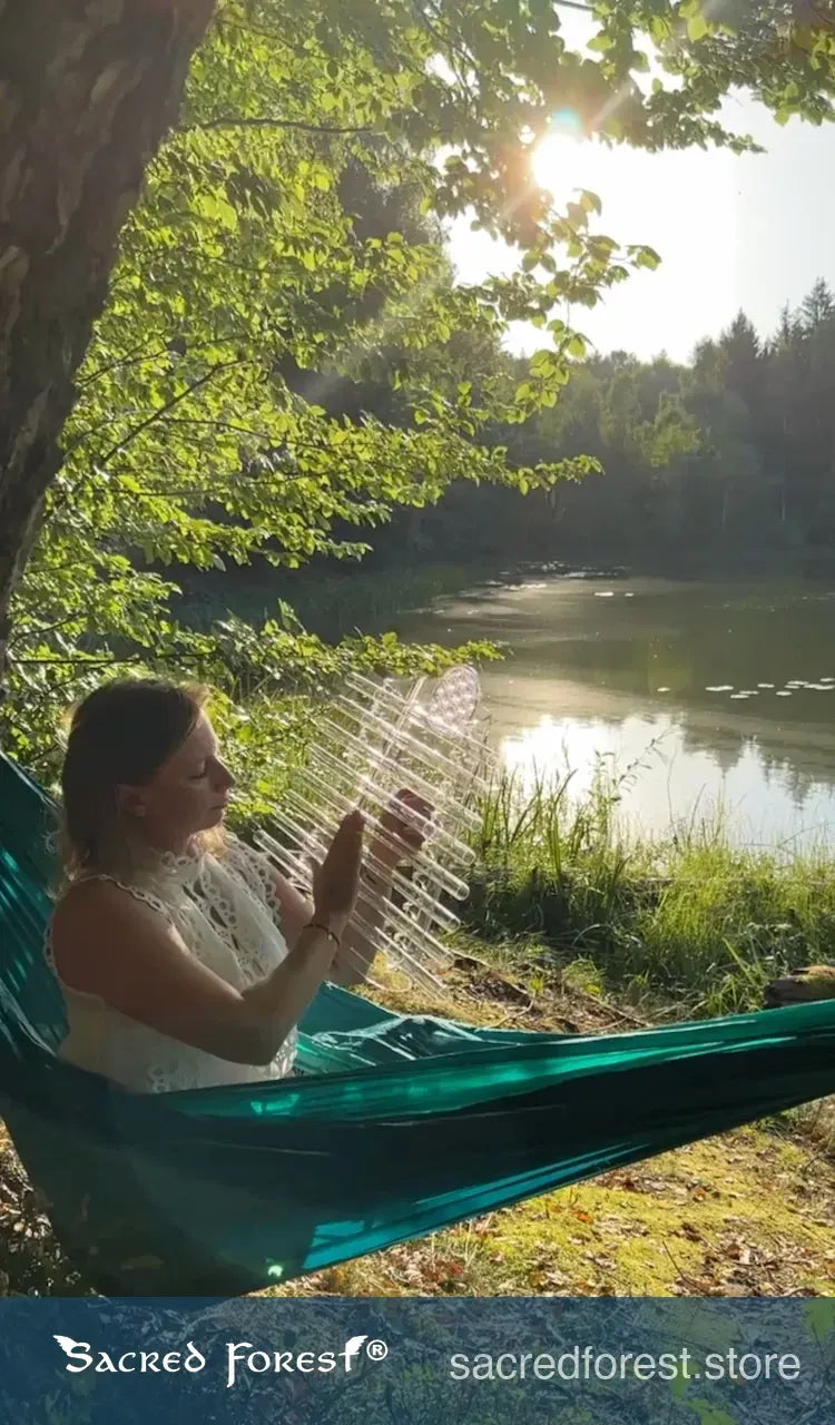 
                    
                      Sacred Forest Crystal Harp in natural forest by the lake relaxing in the hammock
                    
                  