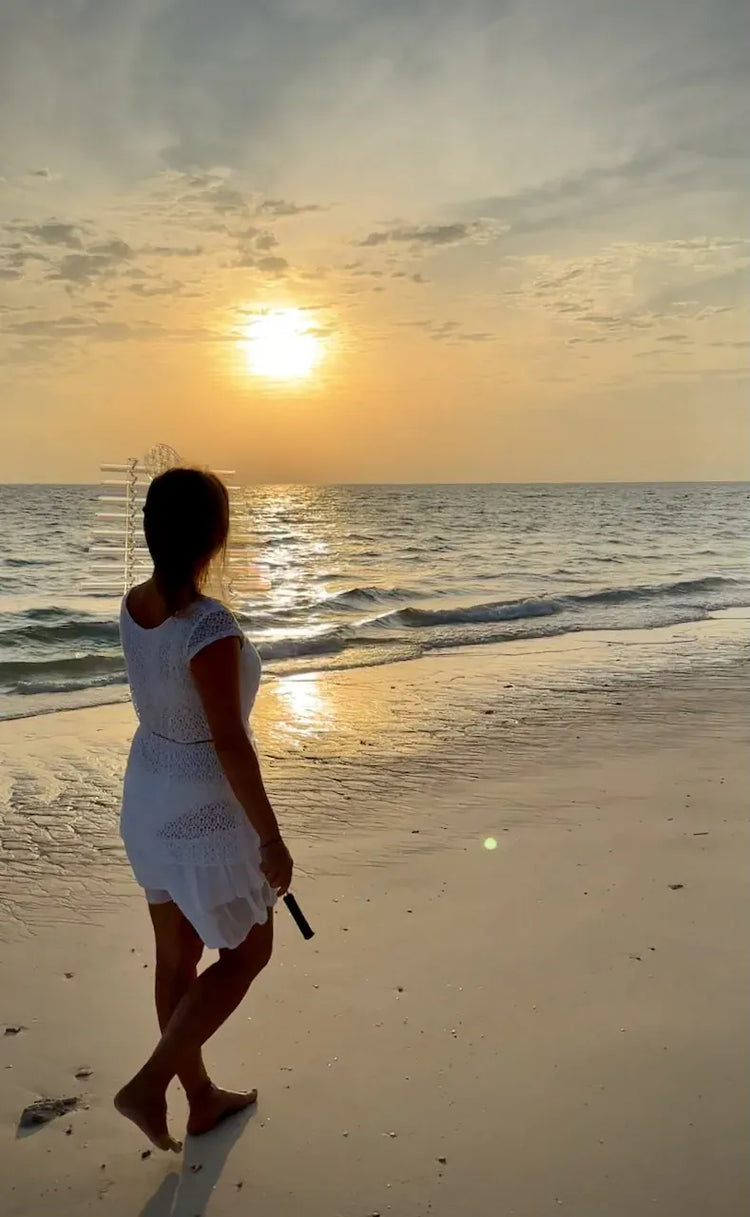 
                    
                      Silhouette of Natalia standing on beach at sunset with Earth Om C# Sacred Forest Crystal Harp looking at sun reflecting on ocean
                    
                  