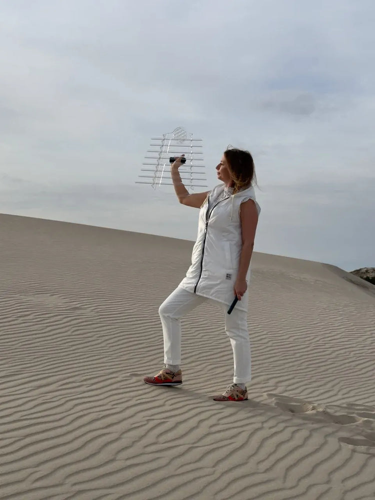 
                    
                      Natalia in white standing on sand dune crest holding Earth Om Cis Sacred Forest Crystal Harp high with rippled sand patterns
                    
                  